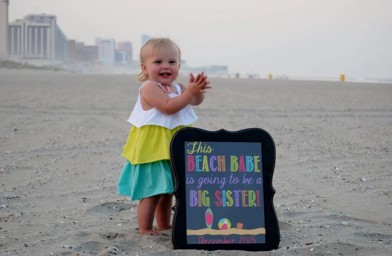 Sibling pregnancy announcement on the beach