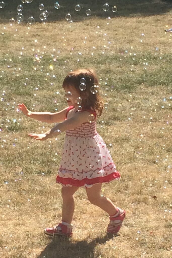 a baby chasing bubbles in the summer