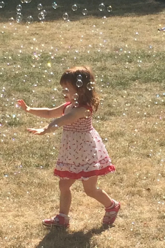 a baby chasing bubbles in the summer